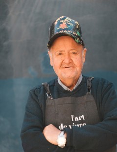 foto de manuel ruiz, artista de l'Art de Viure, portant un davantal amb el logo del taller inclusiu i una gorra negra de Bob Marley