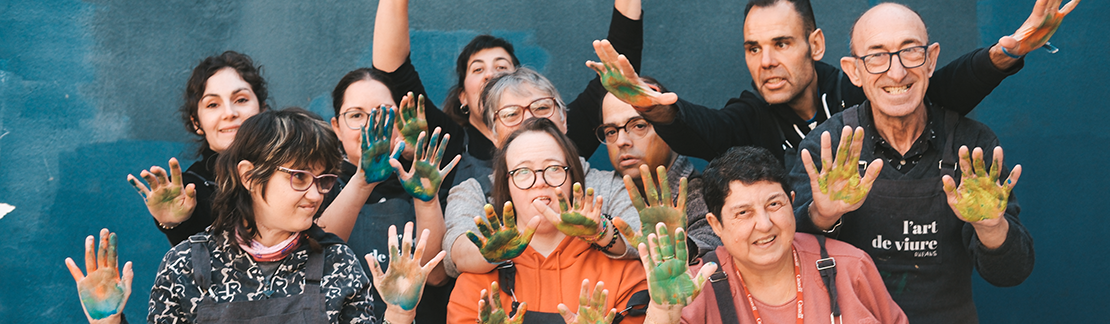 grup d'artistes de l'Art de viure, somrients i mostrant les mans plenes de pintura de colors. 