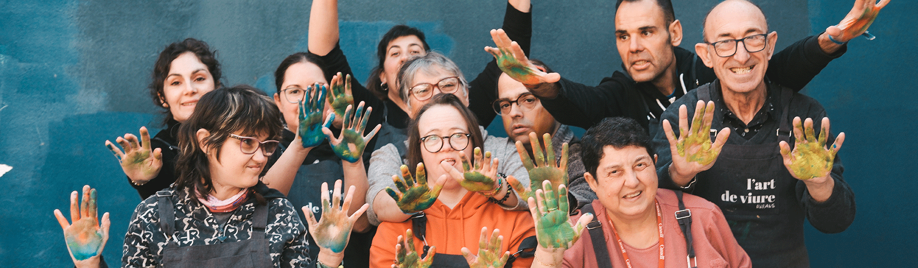 Grup de persones del projecte 'L'Art de Viure' d'AMPANS amb les mans pintades, somrient i mostrant creativitat i inclusió a través de l'art