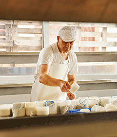 Trabajador elaborando quesos artesanales en las instalaciones de Muntanyola, destacando el compromiso con la calidad y el proyecto agrosocial de AMPANS por la inclusión laboral.